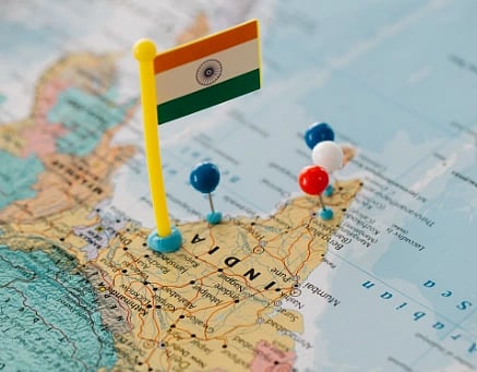 Image of Indian map close-up with a flag and multiple colored pushpins.
