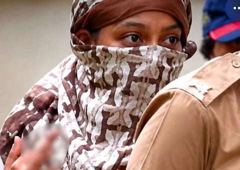 Image of Siya Goyal with her face covered with a scarf except for her eyes. In the image siya goyal is doing an obscene gesture which is blurred. 
