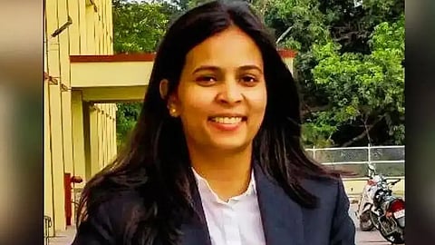 Arfa Usmani wearing suit and looking at camera while standing at a parking