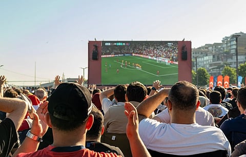 Crowd watching a soccer game on a large screen outdoors in Istanbul, Türkiye.