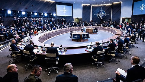 Image shows meeting of leaders from different nations sitting across round table.