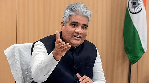 Environment minister Bhupender Yadav sitting at a desk waving his hand to his side.