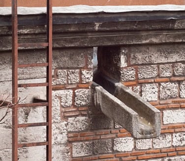 Close-up of a historic brick facade with a rusted ladder and drainpipe in Istanbul, Türkiye.
