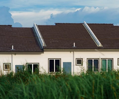 A row of modern houses with gabled roofs against a clear blue sky.
