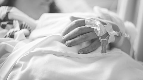 A person in a hospital bed rests with a soft blanket covering them. Their hand, with an IV inserted, conveys a calm and serene atmosphere. What is in WHO Global Cancer Report 2026?