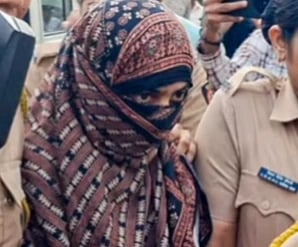 Image of TCS religious conversion case accused Nida Khan walking in police custody. her face is covered and is seen walking among a group of police and media.