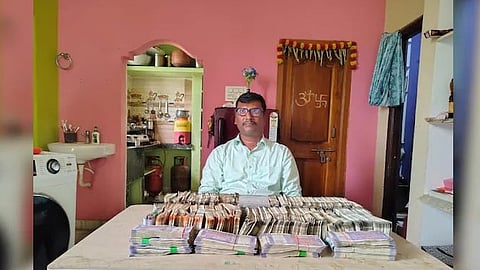 Telangan Municipal engineer  sitting at his home with ₹32 lakh worth of cash in front of him.