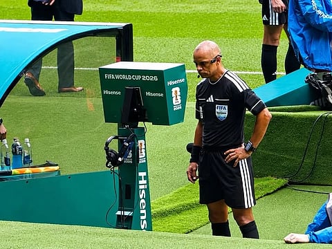 Football referee conducting a Video Assistant Referee (VAR) review during an international match