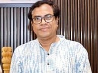 Image of educator Kazi Masum Akhtar standing and posing for a picture. he is wearing a white kurta with light blue patterns.