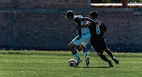 Two soccer players vie for possession during a daytime match.in the image their faces are not visible .