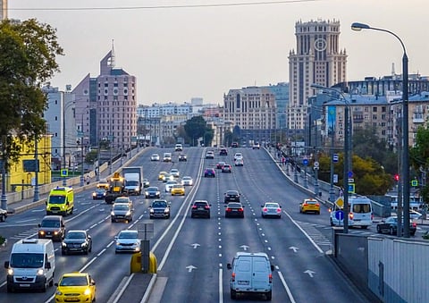A bustling highway in Moscow with iconic city architecture in the background.

