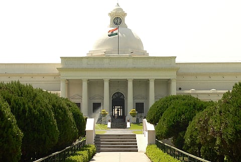 Image of Main Administrative Building IIT Roorkee. In the image a white building with the national flag of India on top of it and at the front greenery can be seen. 