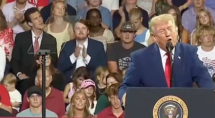 In the image Donald Trump is shown adressing people