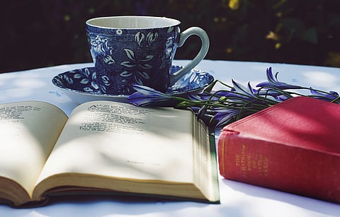 In the image a tea cup is shown with books showcasing literature and poetry
