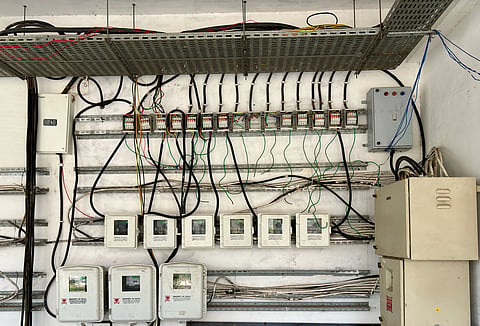 A wall-mounted electrical panel displays numerous meters and cables in an orderly arrangement. The setup conveys a sense of industrial functionality.