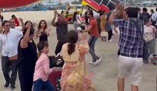 In the image some indians are shown playing Garba in an airport