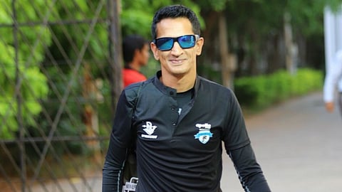 A man facing the camera, wearing a blue googles smiling.