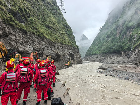 In the image many rescuers are shown in red uniform with flood water in front of them