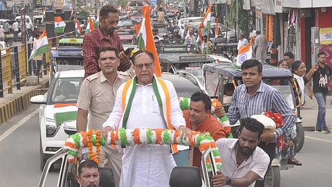 A man wearing the tricolour on his shoulder travels on a car's hood.