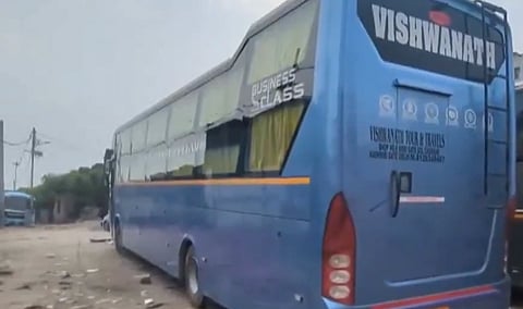 Blue Vishwanath bus labeled “Business Class” and “Vishwanath,” parked on a dusty roadside under a hazy sky; quiet, utilitarian mood.