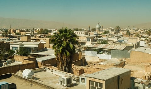 A panoramic view of Shiraz's rooftops, featuring a prominent mosque under a clear blue sky.
