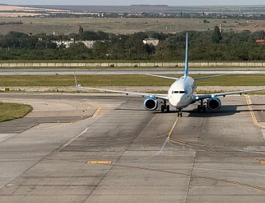 Passenger airplane taxiing on a runway with clear skies and scenic landscape.

