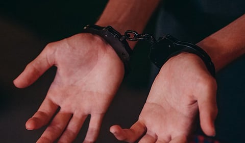 A close-up image showing hands in handcuffs, symbolizing justice and law enforcement.
