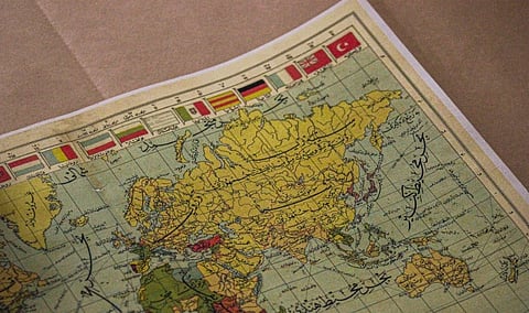 Vintage illustrated map of Asia, with yellow landmasses, country borders, labels, grid lines, and colorful national flags along the top.