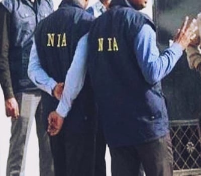 NIA officers standing outside a house.