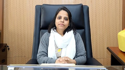IAS Neha Marvya sitting on a desk.