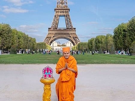 Image of a man wearing a traditional Hindu clothes standing in front of the Eiffel Tower
