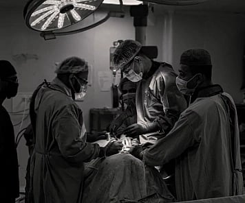 black and white image of Team of surgeons in an operating room conducting surgery in black and white.