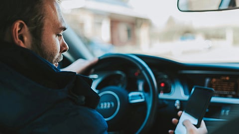 A man driving a car while looking at his cell phone. 
