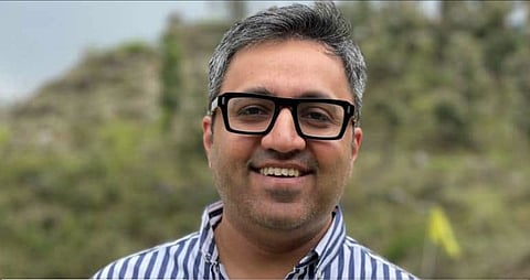A man wearing a specs smiling at the camera.