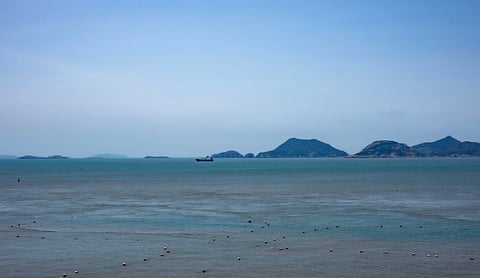 Tranquil seascape of Wenzhou's coast with distant islands under a clear blue sky.
