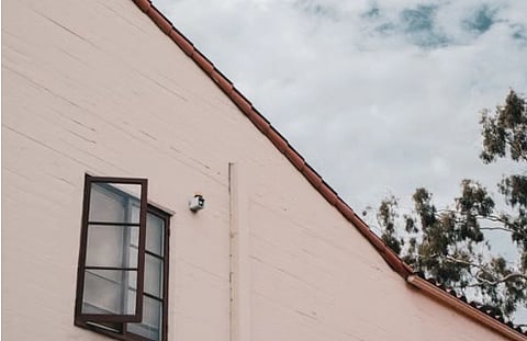 Sunny day view of modern house exterior with open window and red tiled roof.