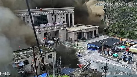 Mudslide debris and thick smoke surround a building at Gyirong Port, with vehicles visible in the foreground.