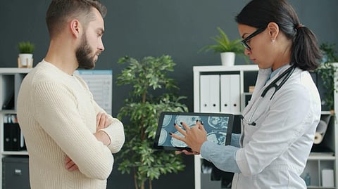 A doctor talking to a patient about something while showing him a Xray