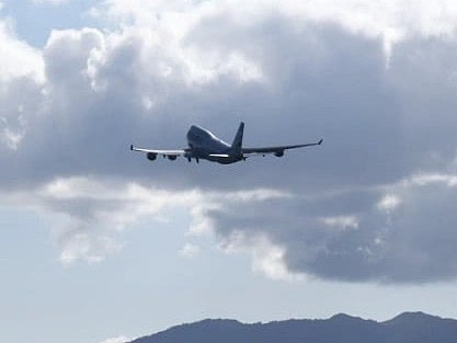 A large airplane takes off over a mountain under a cloudy sky in Geneva, Switzerland.
