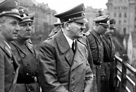 Black and white image of Adolf Hitler and other officials standing and looking towards something. 