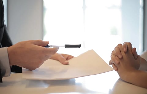 Close-up of a contract signing with hands over documents. Professional business interaction.
