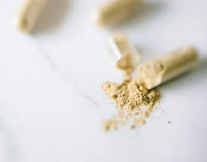 Close-up view of open capsules spilling powder on a marble surface. Ideal for health and supplement topics.
