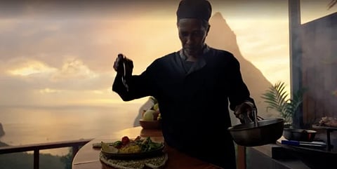 Image of a chef preparing food at resort. behind him is a pretty background