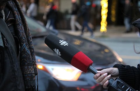 A person being interviewed on a Vancouver street, holding a microphone.
