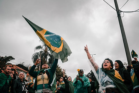A lively demonstration with people waving Brazilian flags on a cloudy day.