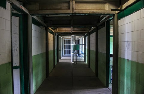View of an empty prison corridor with open cell doors symbolizing security and isolation.
