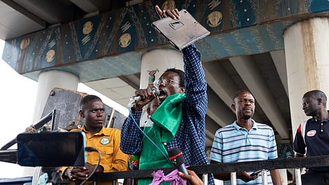 A group of men during a peaceful protest, one holding a microphone and banner.