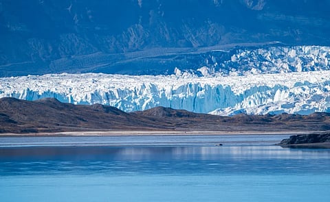Scenic view of a glacier with icy cliffs meeting a tranquil fjord in Svalbard.
