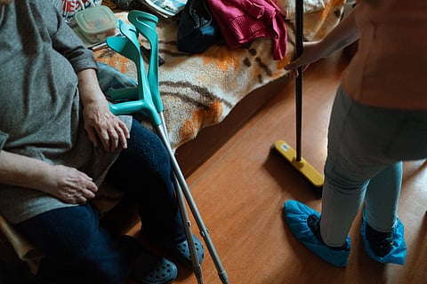 Caregiver helps an elderly woman with cleaning tasks, showcasing home care support.
