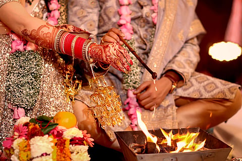 Close-up of traditional Hindu wedding ritual with henna hands over fire.
